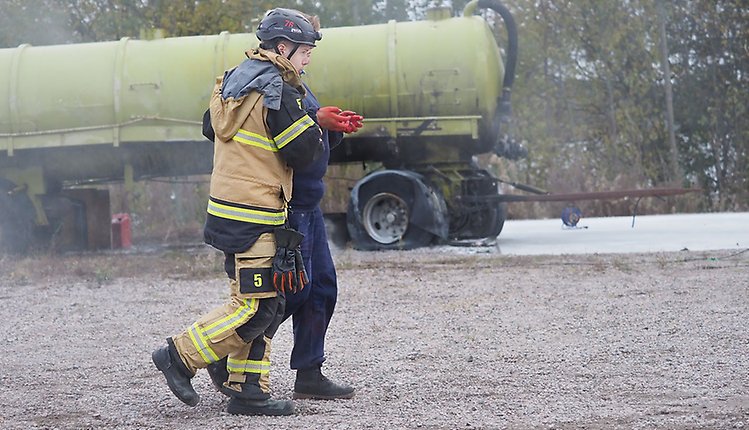 Bild på en brandman som leder bort en skadad person från en olycka.